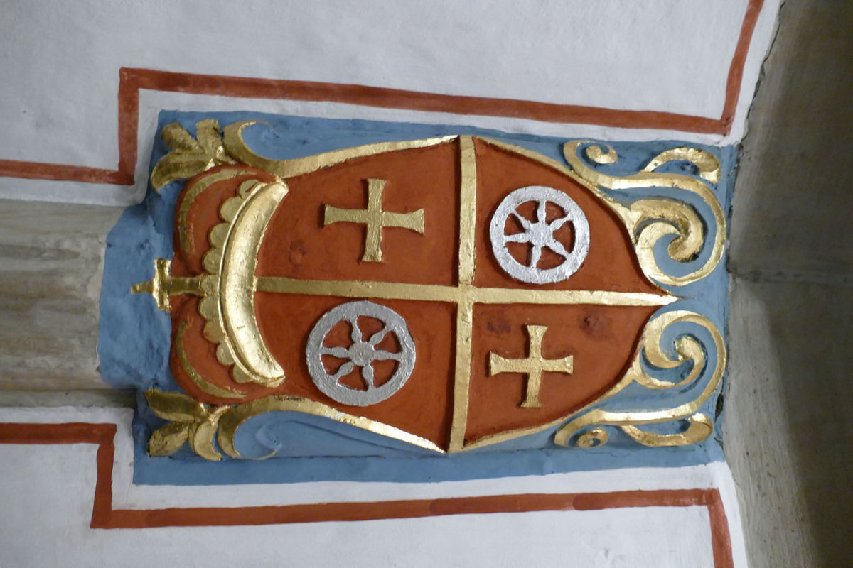 10. Das Kurfürstlisches Wappen in St. Crescentius von Anselm Franz von Ingelheim. Der Naumburger Stadtbrand (1684) und der Wideraufbau der Kirche fanden während der Regierungszeit des Mainzer Erzbischofs Anselm Franz Reichsfreiherr von Ingelheim (1680-1695) statt. Im hölzernen Gewölbe des Langhauses zeigt eine Wappenkartusche am Anfall der Scheitelrippe an den Triumphbogen sein Wappen. Die Kartusche zeigt die Formen des ausgehenden 17. Jahrhunderts. Das Wappen ist wie folgt blasoniert: „Geviert und in Rot ein sechsspeichiges Rad (Erzstift Mainz) und in Schwarz ein von Gold und Rot in zwei Reihen geschachtetes Kreuz (Familienwappen Ingelheim).